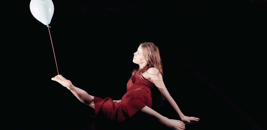 Women in red holding balloon with her foot - fall and float play theatre
