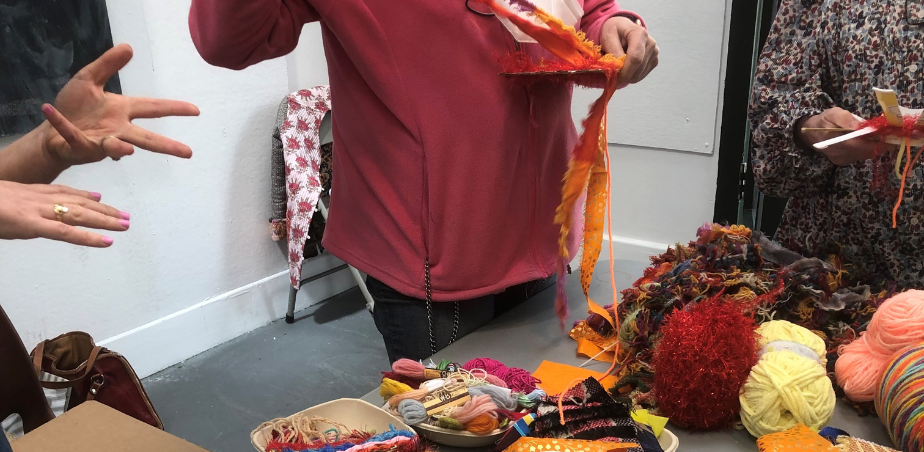 Participants in a workshop stood around a table with wool, fabric and textile embellishments
