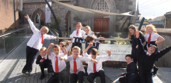 A group of primary school children smiling and posing outside Highlanes arts centre