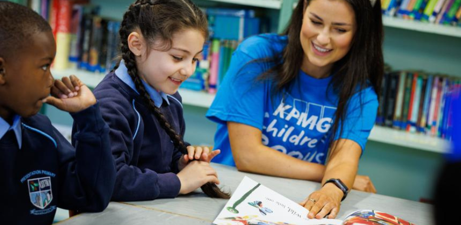 An artist sitting with two schoolchildren looking at some books as part of Children's Books Ireland Junior Juries programme