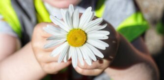A child holds a daisy