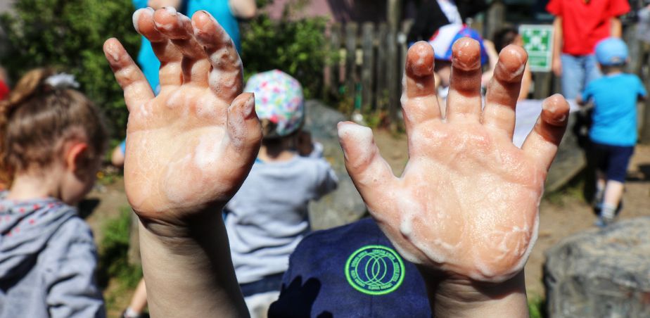 Close up of the open palms of a child's hands covered in soap bubbles