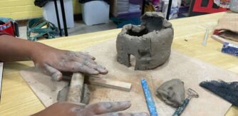 primary school student hands roll out some clay
