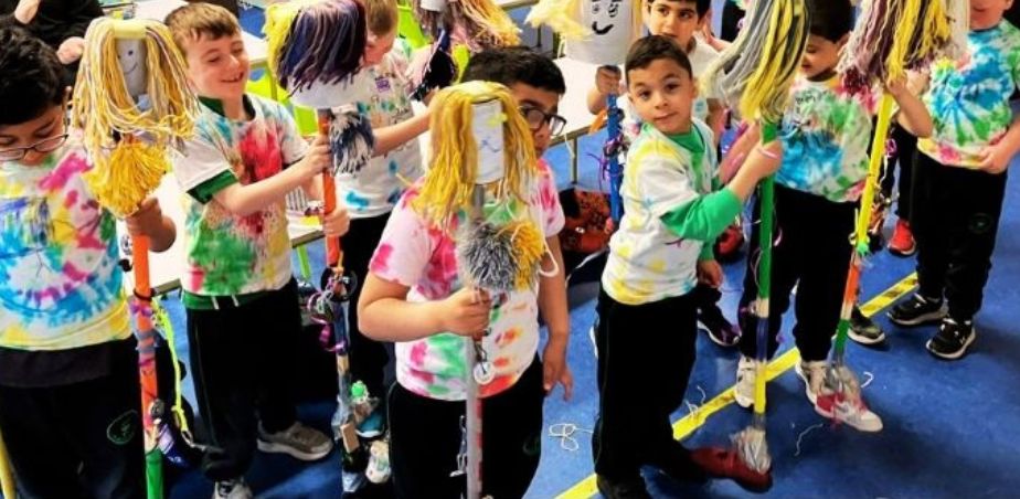 A group of school students wearing colourful t-shirts and characters made from floor mops