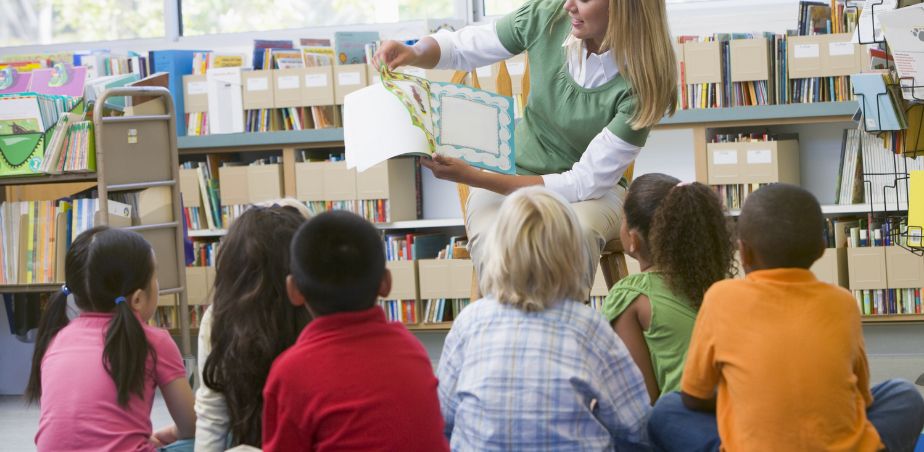 Teacher reading from a book to school children in a classroom