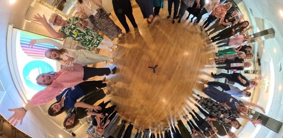 People stand in a circle smiling up at camera