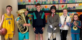Group of children with musical instruments stand in front of colourful artwork for Creative Youth Programme announcements