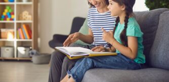 Mother and daughter sit on a sofa reading together - Blog 3 Dr Claire Dunne