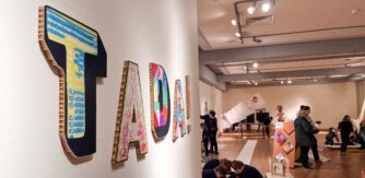 Colourful cardboard letters on a gallery wall spell TADA