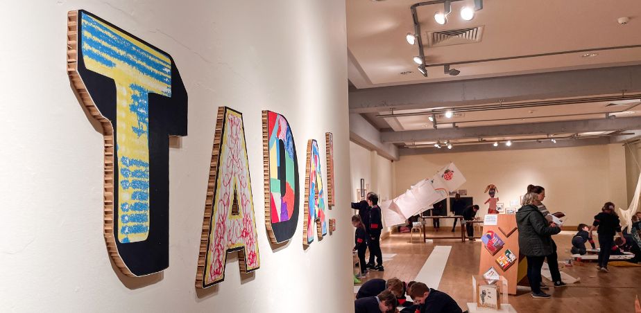 Colourful cardboard letters on a gallery wall spell TADA